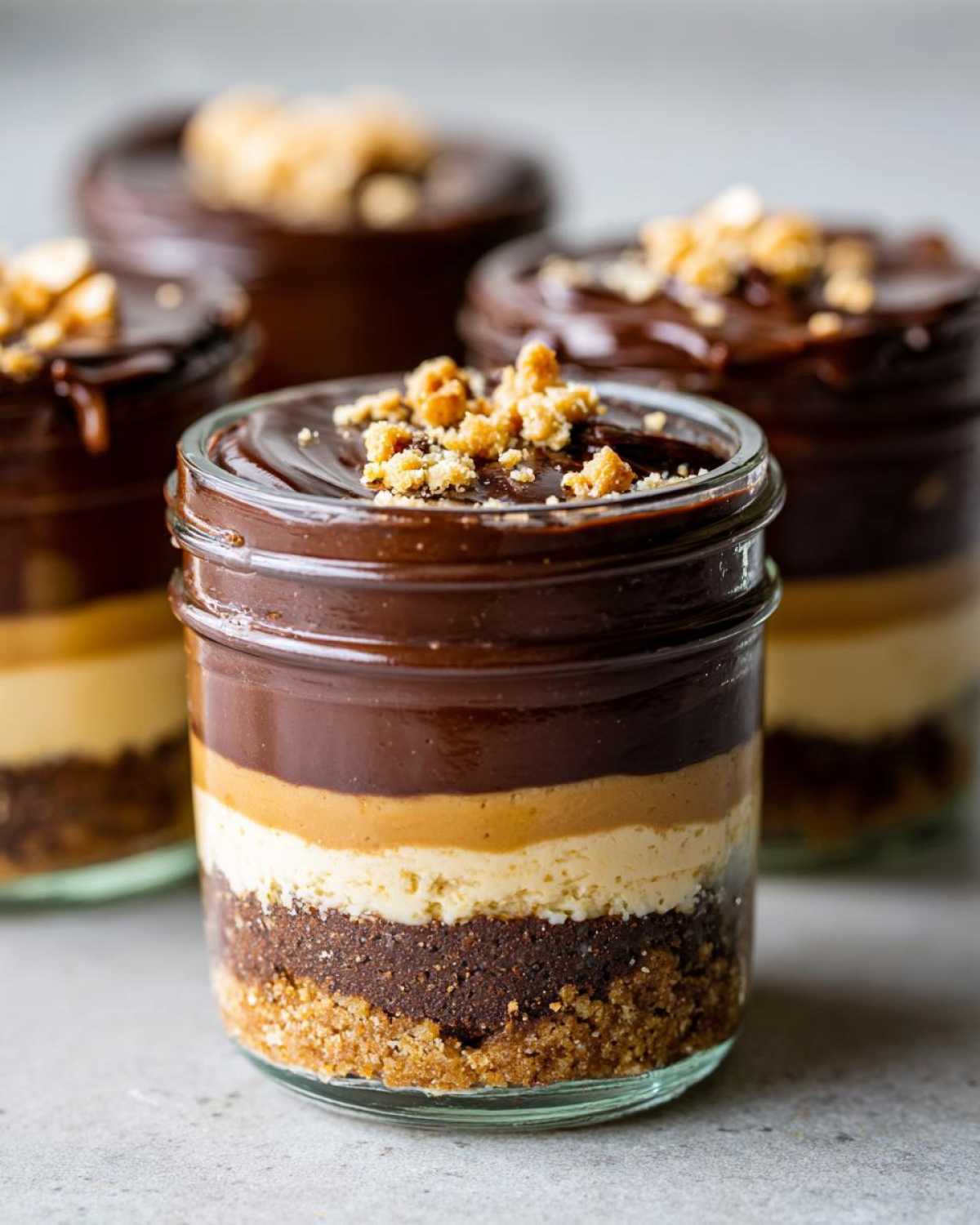 Close-up of a No-Bake Chocolate Peanut Butter Pie Jar showing layers of crust, filling, and chocolate topping with crushed nuts.