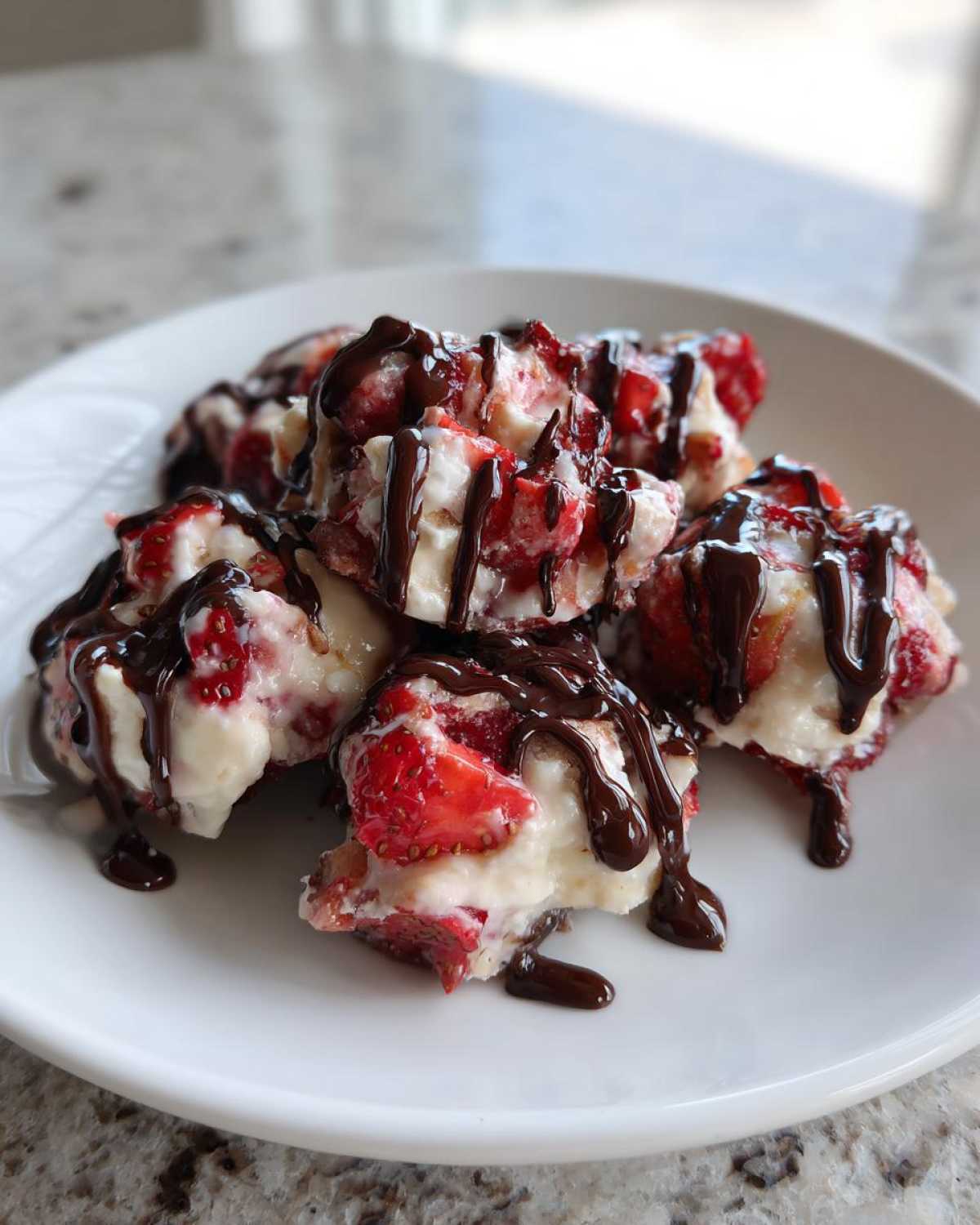Close-up of several No-Bake Chocolate Strawberry Yogurt Clusters drizzled heavily with melted chocolate.