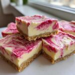 Close-up of stacked squares of No-Bake Lemon Strawberry Cheesecake Bark with a graham cracker crust and pink swirl topping.