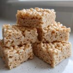 A close-up stack of five chewy No-Bake Peanut Butter Rice Cereal Bars on a light countertop.