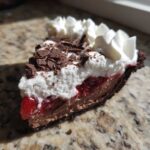 Close-up of a slice of No-Bake Strawberry Chocolate Pudding Pie with layers of chocolate, strawberry filling, and whipped cream.