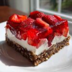 A perfect square slice of No-Bake Strawberry Pretzel Dessert Bars showing three distinct layers: pretzel crust, cream cheese filling, and strawberry gelatin topping.