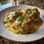 Three golden chicken thighs smothered in a creamy lemon dill sauce and topped with fresh dill.