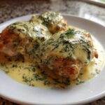 Three pieces of One-Pan Creamy Lemon Dill Chicken Thighs generously covered in a rich, pale yellow sauce speckled with fresh dill.