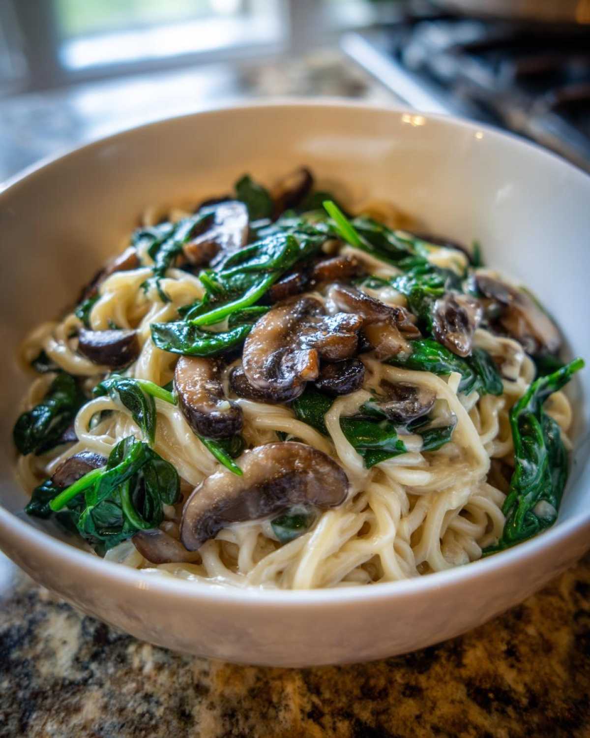 A close-up of One-Pot Creamy Mushroom Spinach Ramen served in a white bowl, featuring creamy noodles, sautéed mushrooms, and wilted spinach.