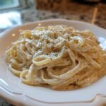 A close-up of fettuccine pasta coated in creamy Easy Cottage Cheese Alfredo Sauce and sprinkled with herbs.