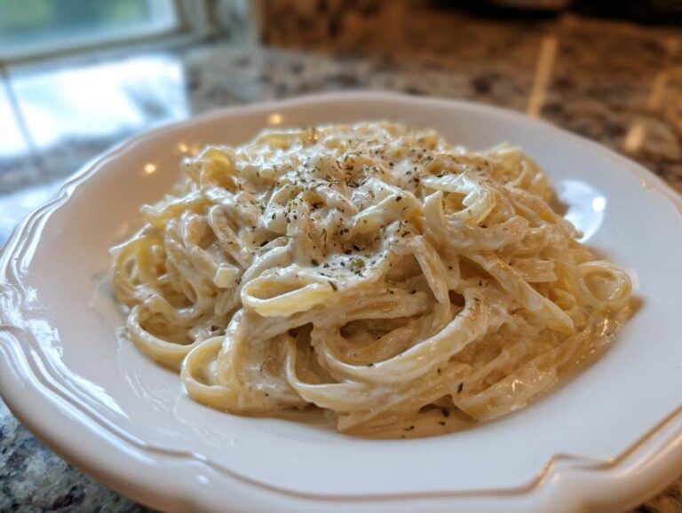 A close-up of fettuccine pasta coated in creamy Easy Cottage Cheese Alfredo Sauce and sprinkled with herbs.