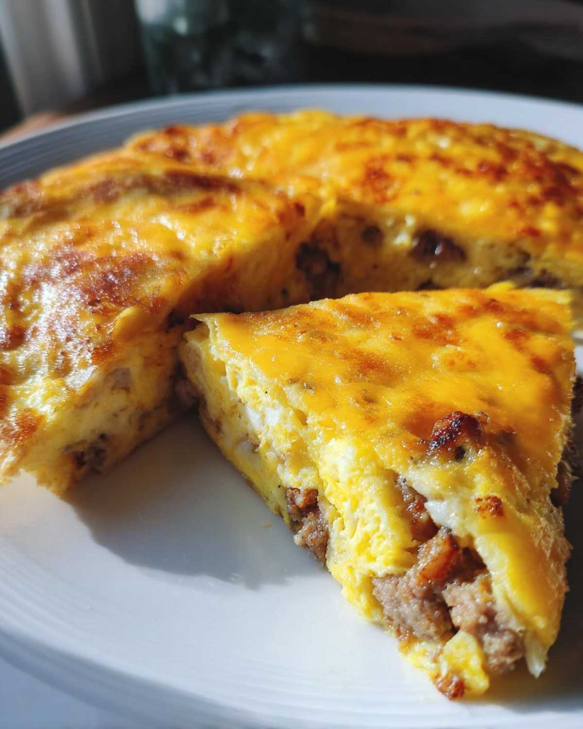 Close-up of a thick slice of Sheet Pan Breakfast Quesadillas showing sausage filling inside the baked egg and cheese mixture.
