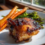 Close-up of a perfectly glazed Sheet Pan Ginger Orange Chicken Thighs served with roasted carrots and broccoli.