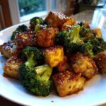 Close-up of crispy Sheet Pan Sweet Chili Tofu with Broccoli florets coated in a glossy sauce and sesame seeds.