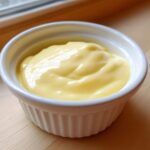 Close-up of thick, creamy Vegan Creamy Lemon Tahini Dressing in a small white fluted ramekin.