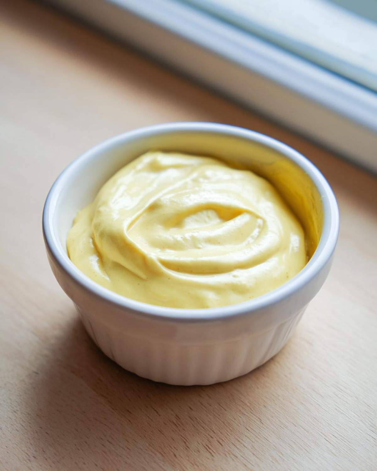 A close-up of thick, creamy Vegan Creamy Lemon Tahini Dressing in a small white ramekin.
