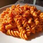 Close-up of Vegan Creamy Roasted Red Pepper Hummus Pasta made with fusilli, topped with spices.