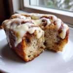 A close-up of a sliced Banana Bread Cinnamon Rolls Dessert topped with thick white icing.