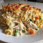A generous serving of creamy Chicken Noodle Casserole with shredded chicken, peas, carrots, and a golden baked topping.