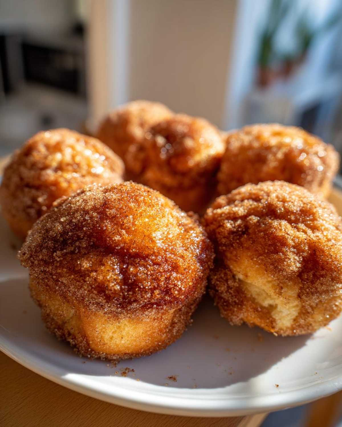 Several golden-brown pieces of Cinnamon Donut Bread Pull Apart coated heavily in cinnamon sugar, sitting on a white plate.