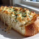 A thick slice of ESPECIALLY CHEESY GARLIC BREAD showing melted, stringy cheese pulling away from the soft interior.