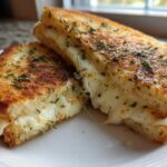 Close-up of a perfectly grilled Garlic Bread Grilled Cheese sandwich cut in half, showing gooey, melted cheese.