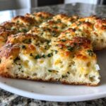 A close-up cross-section of homemade Cheese Bread showing gooey melted cheese inside and a golden, herbed topping.