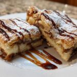 Three squares of Salted Caramel Pop Tart Bars Cinnamon Sourdough drizzled with caramel and dusted with powdered sugar.